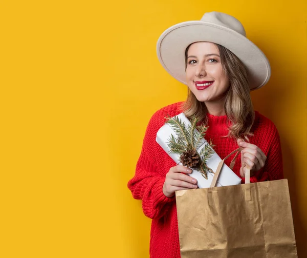 Lachende vrouw in rode trui met geschenk doos en boodschappentas — Stockfoto