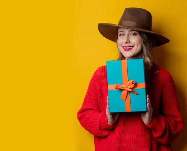 Jovem mulher sorridente em camisola vermelha com caixa de presente — Fotografia de Stock