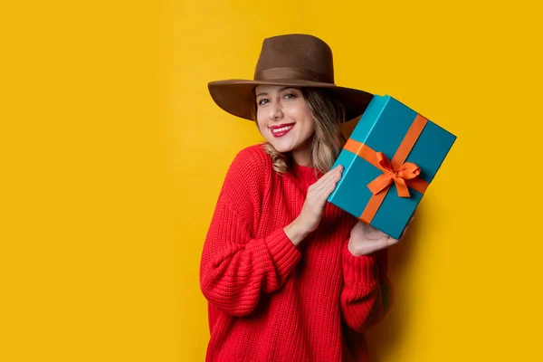 Giovane donna sorridente in maglione rosso con confezione regalo — Foto Stock