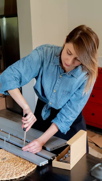Mulher com chave de fenda instalando um mobiliário em casa pessoalmente — Fotografia de Stock