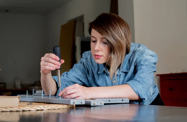 Mulher com chave de fenda instalando um mobiliário em casa pessoalmente — Fotografia de Stock