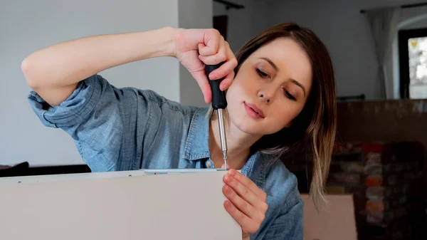 Mulher com chave de fenda instalando um mobiliário em casa pessoalmente — Fotografia de Stock