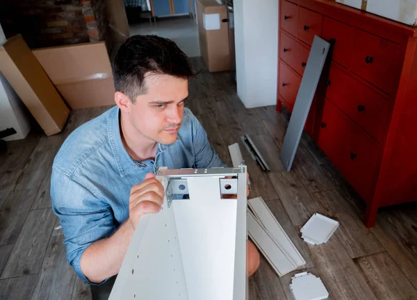 Jovem com chave de fenda instalando uma mobília — Fotografia de Stock