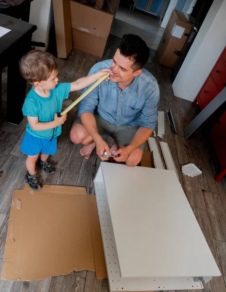 Jovem com chave de fenda e uma criança estão instalando uma mobília — Fotografia de Stock