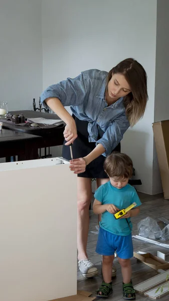 Mère avec tournevis et un enfant installe un mobilier — Photo