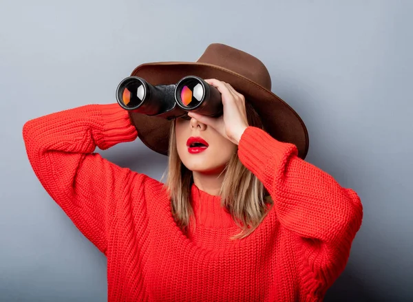 穿红色毛衣和帽子的妇女，用双筒望远镜 — 图库照片
