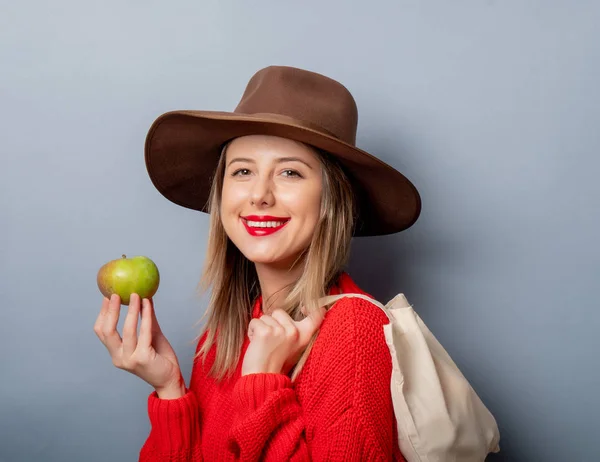 Vrouw in rode trui met appel en tas — Stockfoto