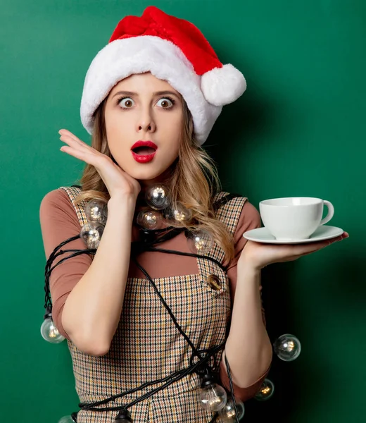 Mujer con luces de Navidad y taza de café sobre fondo verde —  Fotos de Stock