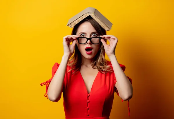 Hermosa mujer en vestido rojo con libro sobre fondo amarillo —  Fotos de Stock