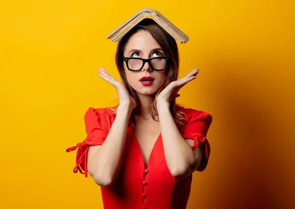 Schöne Frau in rotem Kleid mit Buch auf gelbem Hintergrund — Stockfoto