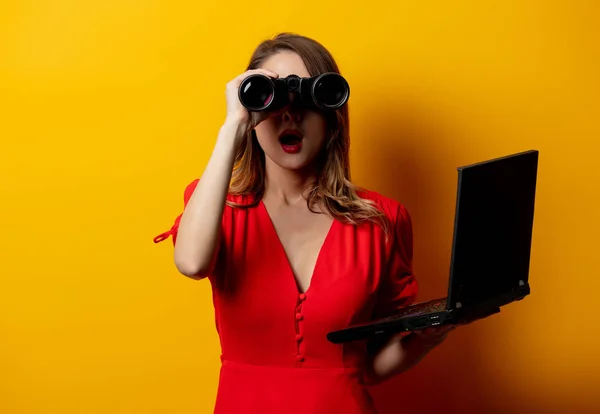 Žena v červených šatech s dalekohledem a notebookem — Stock fotografie