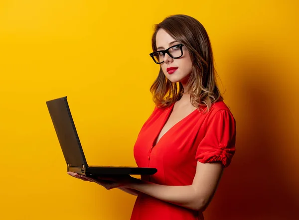 Красива жінка в червоній сукні з ноутбуком на жовтій спині — стокове фото
