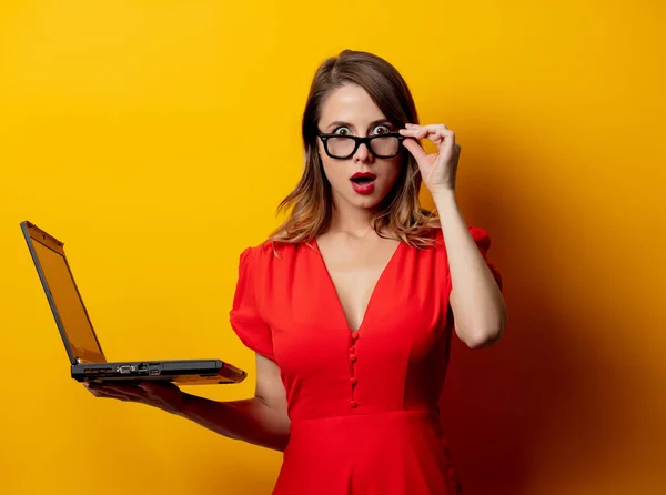 Mulher bonita em vestido vermelho com computador portátil na parte traseira amarela — Fotografia de Stock
