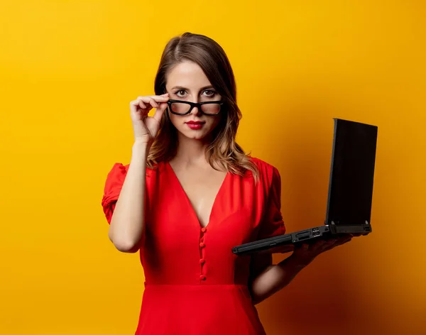Hermosa mujer en vestido rojo con ordenador portátil en la espalda amarilla —  Fotos de Stock