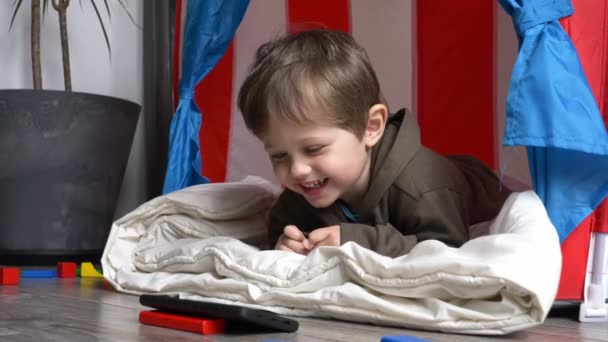 小さな幼児男の子で家で漫画を見ます上の携帯電話でホーム — ストック動画