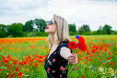 Yazın gelincik tarlasında güzel elbiseli sarışın kız.