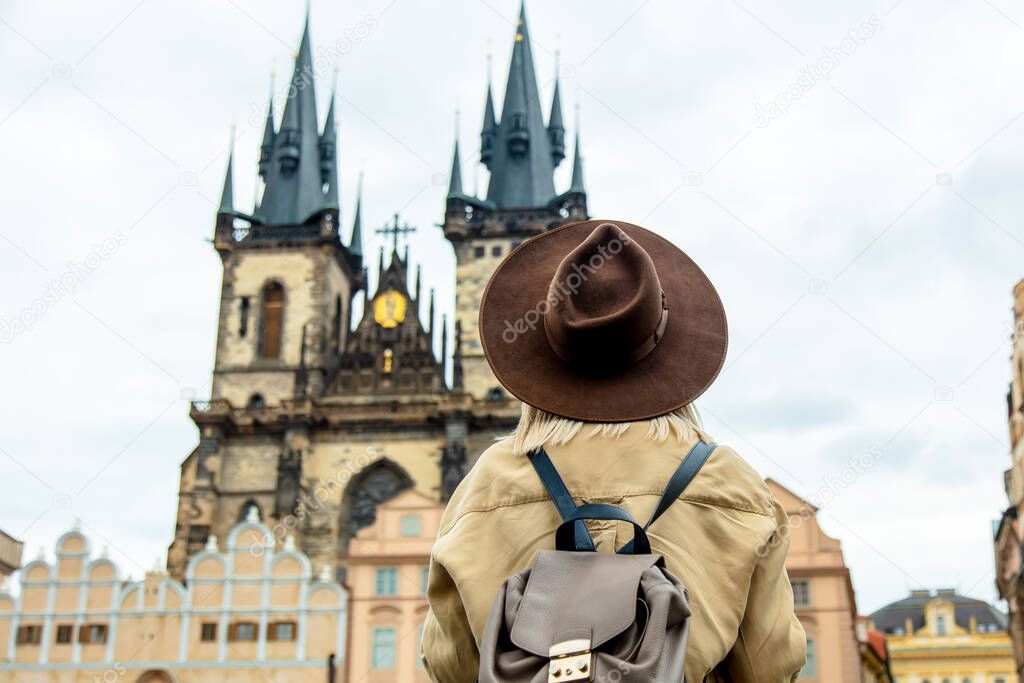 Blonde woman in hat and backpack at central square in Prague, Czech Republic