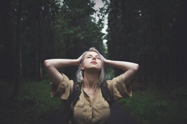 Ormanda yağmurlu bir günde sırt çantalı sarışın kadın. 