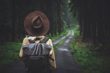 Ormanda yağmurlu bir günde sırt çantalı sarışın bir kadın.