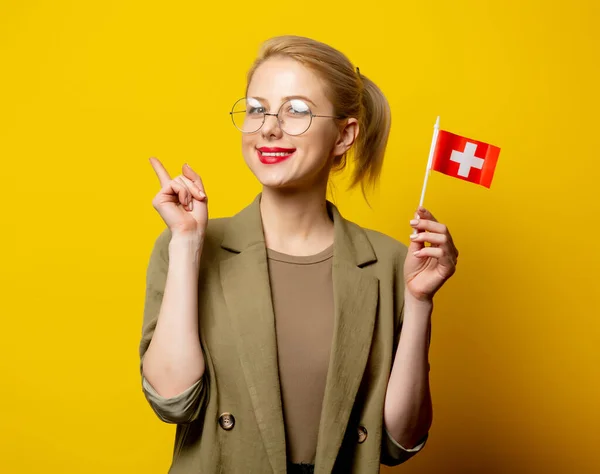 Sarı Arka Planda Sviçre Bayrağı Olan Ceketli Şık Sarışın Kadın — Stok fotoğraf