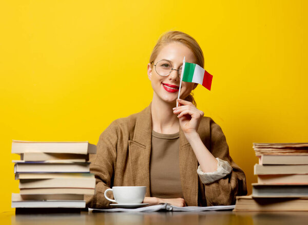 blonde woman with flag of Italy and books on yellow background