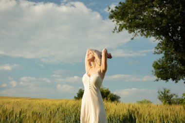 Gün batımında buğday tarlasında güzel sarışın kız 