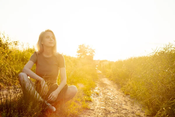 Schöne Blonde Mädchen Sitzt Auf Landstraße Bei Sonnenuntergang — Stockfoto