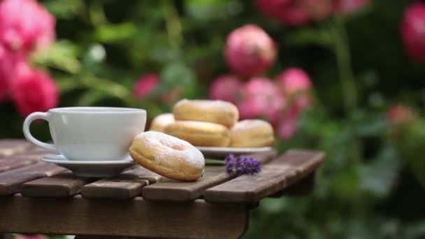 Tasse Kaffee und Donuts auf einem Holztisch im Garten