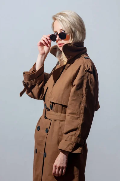 Blondes Mädchen Mit Sonnenbrille Und Mantel Auf Grauem Hintergrund — Stockfoto