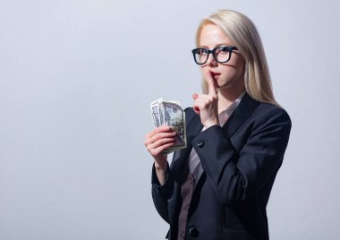 Gri arka planda parası olan takım elbiseli güzel sarışın iş kadını.