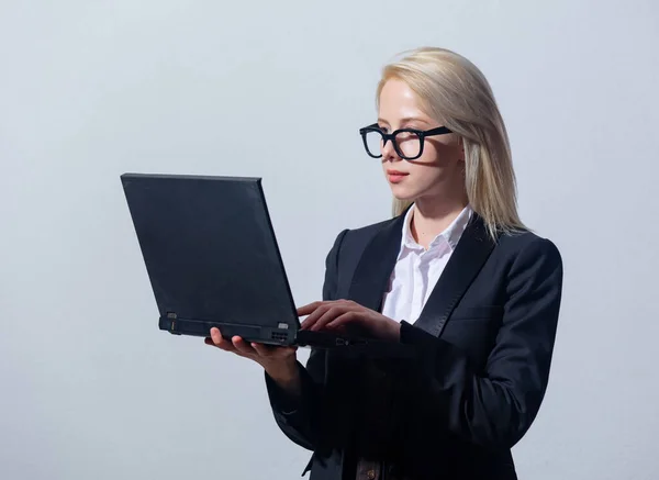 美しいですブロンドビジネス女性でスーツにラップトップコンピュータ上のグレーの背景 — ストック写真