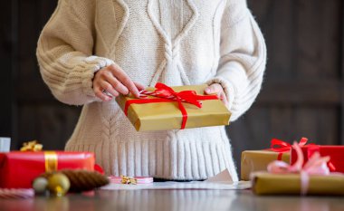 Kazaklı kadın Noel hediyesini masaya sarıyor. 