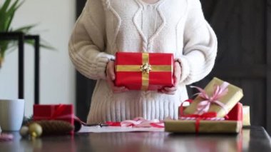 Kazaklı kadın Noel hediyesini masaya sarıyor.