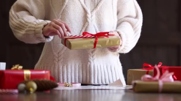 Frau Pullover Wickelt Ein Weihnachtsgeschenk Auf Einen Tisch — Stockvideo