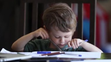 Küçük çocuk babasının evindeki iş yerinde kalemlerle oynuyor.