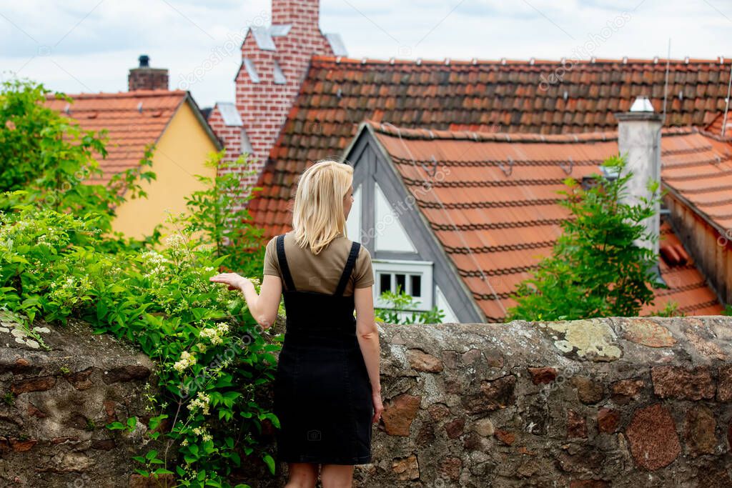 blonde girl stay near old city tile houses in Europe