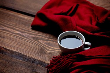 Tahta masada bir fincan kahve ve eşarp. 