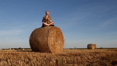 Sarışın kız gün batımında samanlıkta yuvarlanıyor.