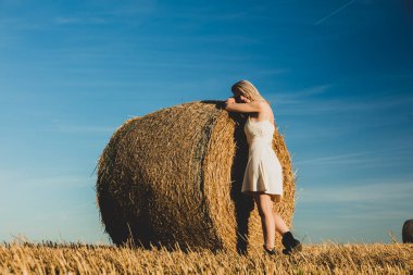 Sarışın kız gün batımında samanlıkta yuvarlanıyor.