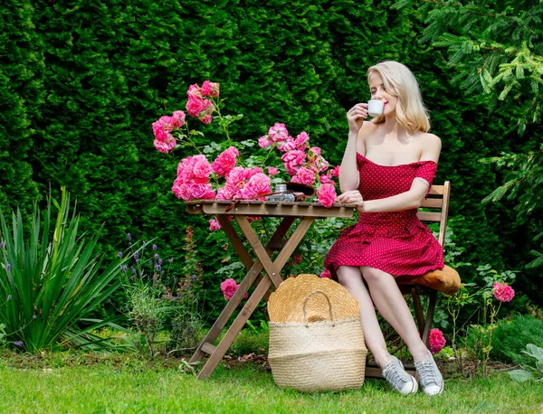 Vacker Blond Flicka Röd Klänning Dricka Kaffe Trädgård — Stockfoto