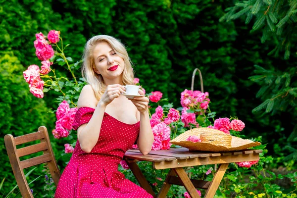 Vacker Blond Flicka Röd Klänning Dricka Kaffe Trädgård — Stockfoto
