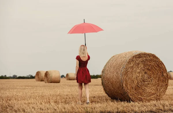 雨の前の小麦畑に傘を差した赤いドレスのブロンド — ストック写真