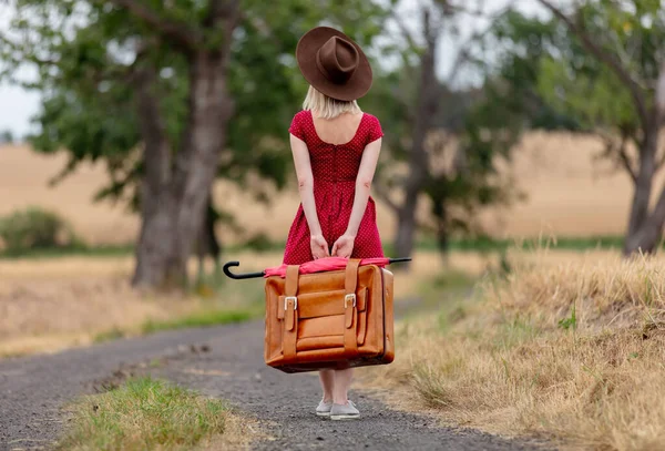 Blondine Roten Kleid Mit Koffer Auf Einer Landstraße Vor Dem — Stockfoto
