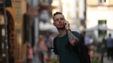 Rastalı genç adam şehir caddesinde telefonla konuşuyor.