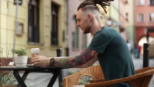 Telefonu Kahvesi Olan Genç Adam Şehirdeki Bir Kafede Oturuyor — Stok video