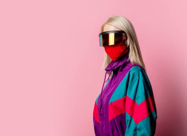 Yüz maskeli bir kadın ve pembe arka planda 3D gözlükler.