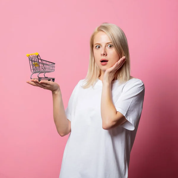 Blond Vrouwtje Wit Moch Tshirt Met Winkelwagentje Roze Achtergrond — Stockfoto