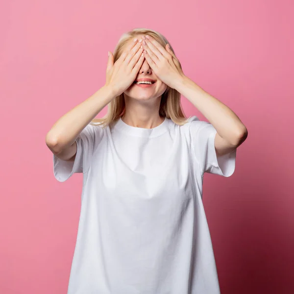 ブロンド女性でホワイトMoch Tシャツ上のピンクの背景 — ストック写真