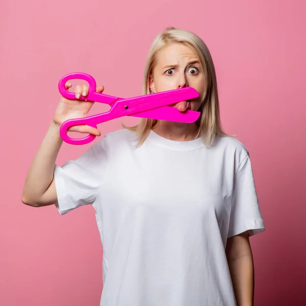 ブロンド女性でホワイトMoch Tシャツともに大きなはさみでピンクの背景 — ストック写真