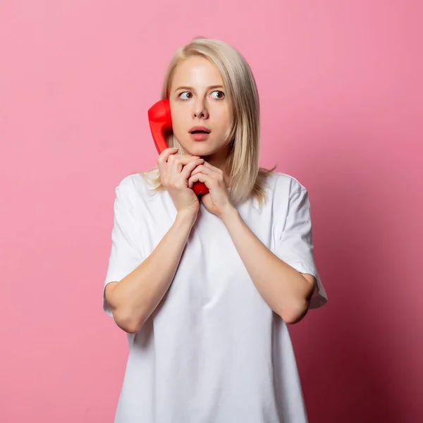 Pembe Arka Planda Kırmızı Bir Cep Telefonu Olan Beyaz Tişörtlü — Stok fotoğraf